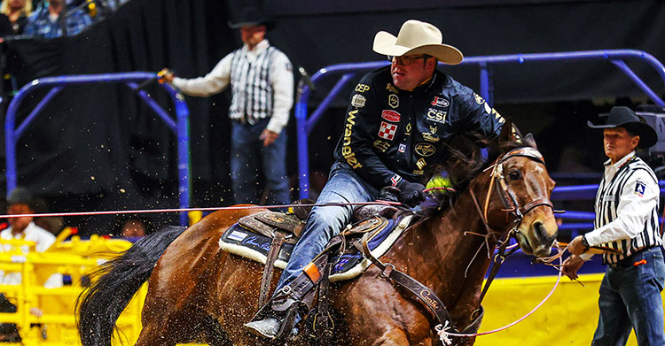 Coleman Proctor, wearing a black shirt, riding a brown horse at the National Finals Rodeo (NFR.)